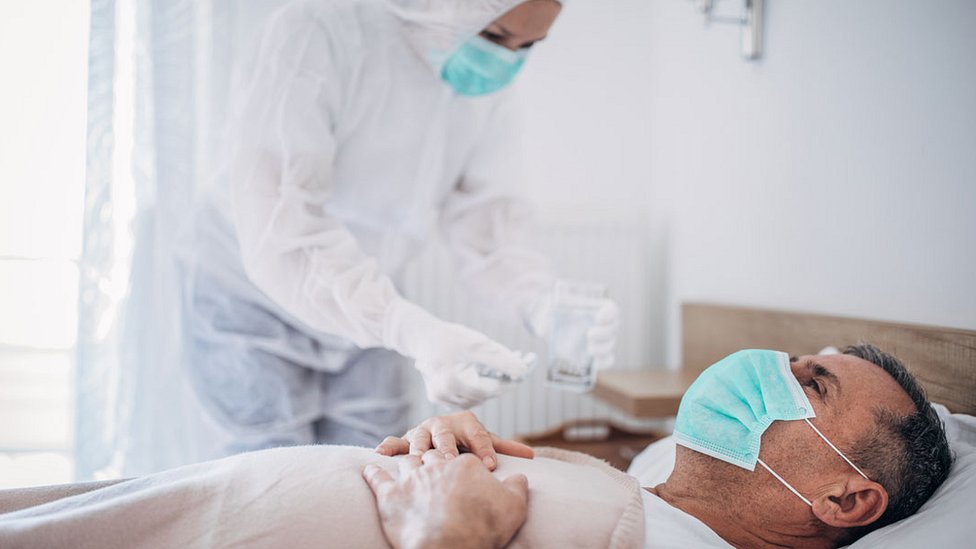 мужчина в маске на больничной койке с медиком в полных СИЗ