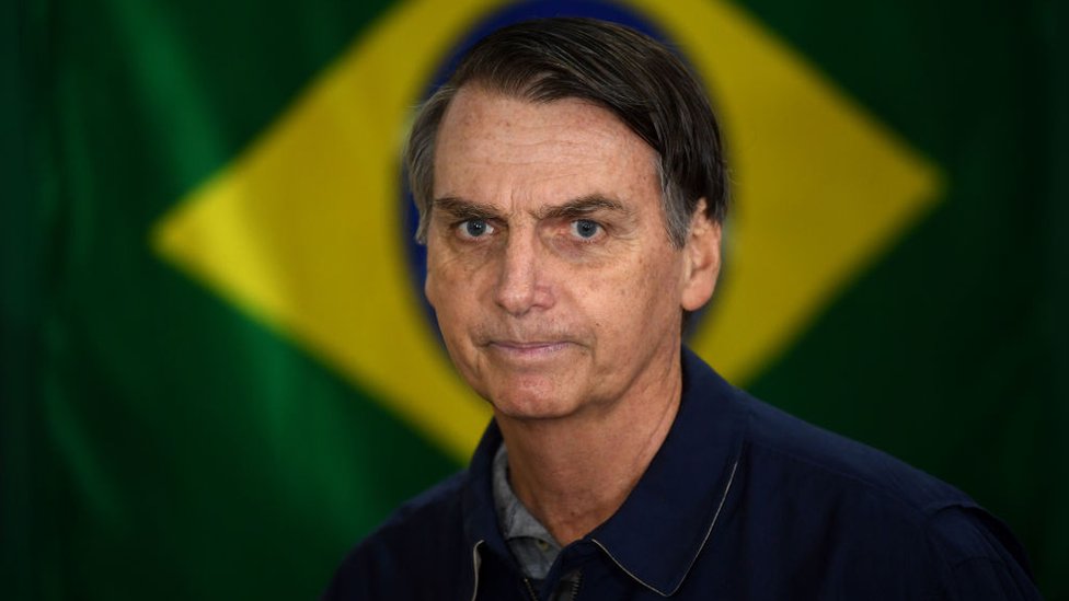 Jair Bolsonaro sobre una bandera de Brasil,