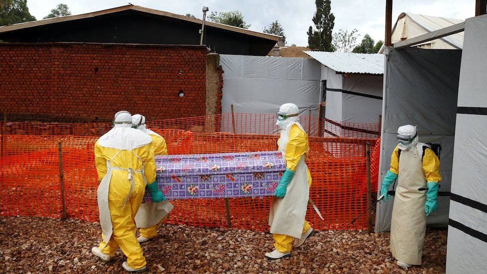 Health workers dressed in protective suits carry a coffin with the body of Congolese woman who died of Ebola in Butembo, DRC on 28 March 2019