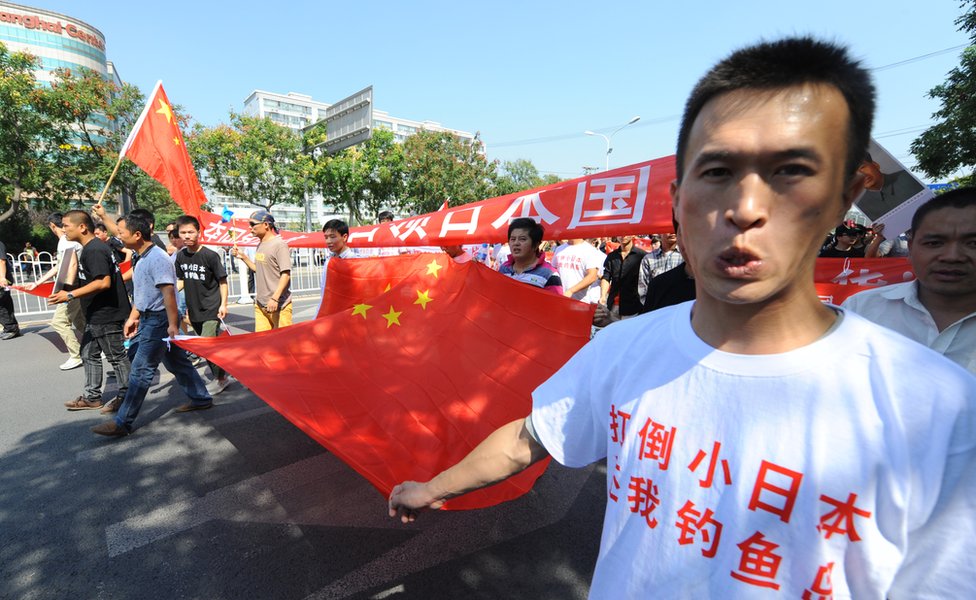 Chinese demonstraters hold banners as they march past the Japanese embassy during a protest over the Diaoyu islands issue, known as the Senkaku islands in Japanese, in Beijing on September 16, 2012.