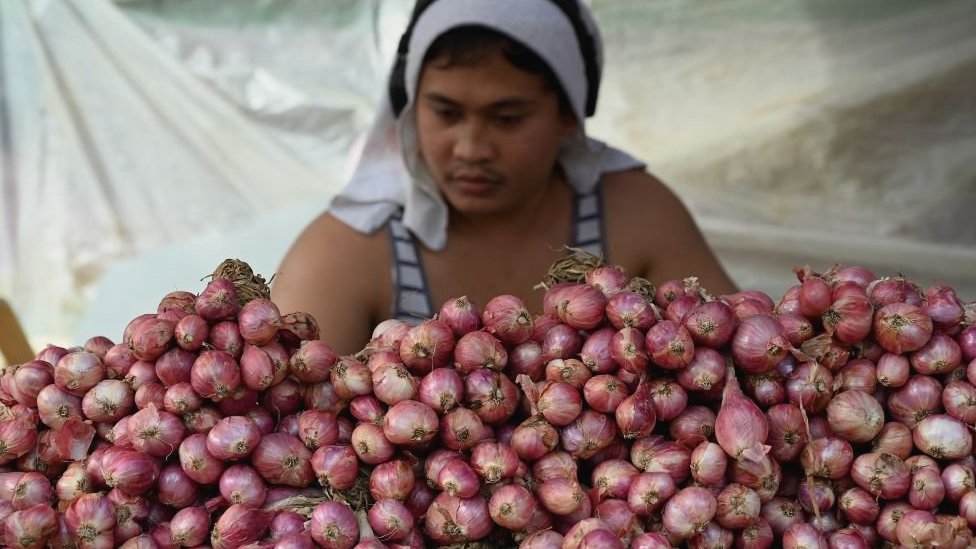 A vendor sells onions at a market in Manila.