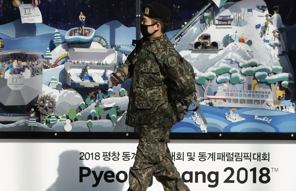 Южнокорейский солдат проходит мимо пиар-стенда Зимних Олимпийских и Паралимпийских игр в Пхенчхане в 2018 году, 5 января 2018 года