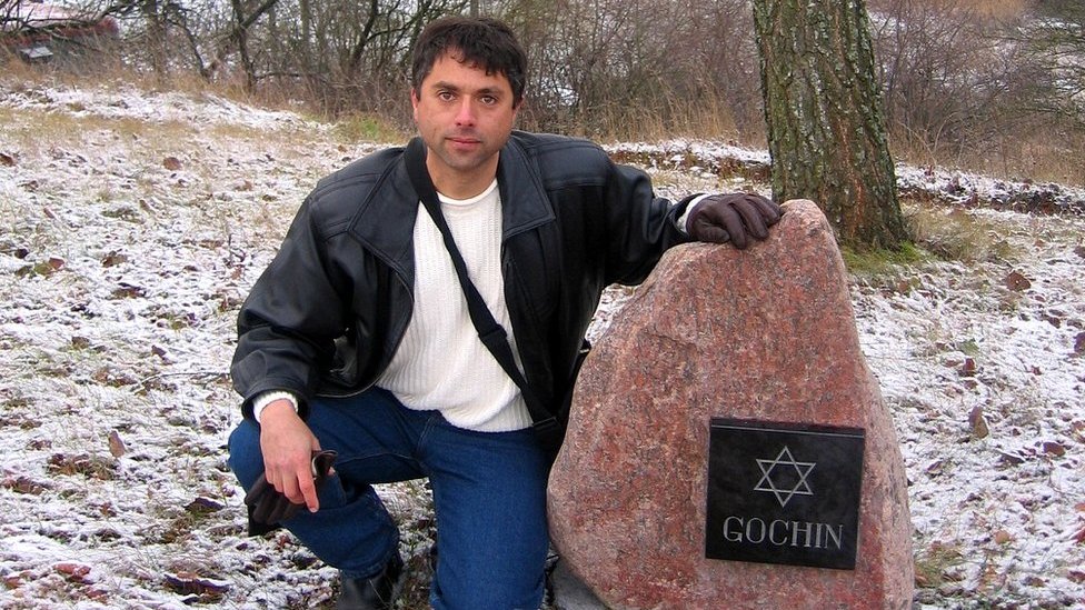 Berikan Guchin di sebelah monumen untuk kerabatnya di Lituania