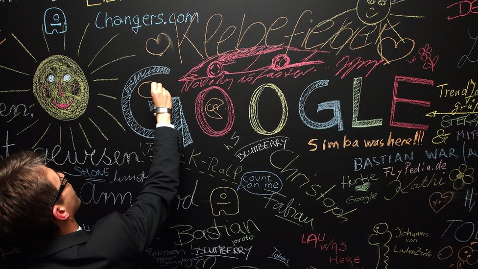 Un hombre escribe en un pizarrón donde se lee la palabra "Google", entre otras.