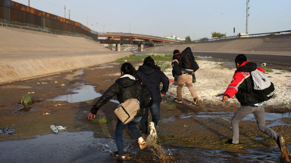 Un grupo de personas corre en el Río Bravo, en el punto de control del Paso del Norte, en Ciudad Juárez.