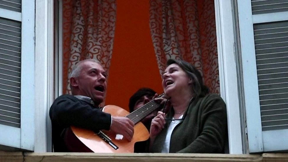 Hombre y mujer cantando desde una ventana en Italia