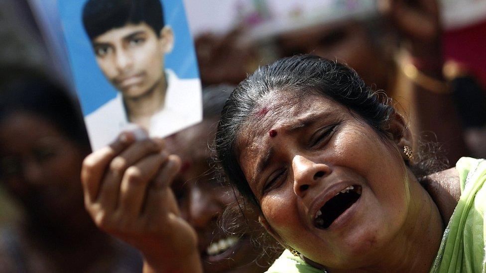 Сохраните фотографию плачущей тамильской женщины, держащей фотографию пропавшего члена семьи во время протеста 2013 года в Джафне