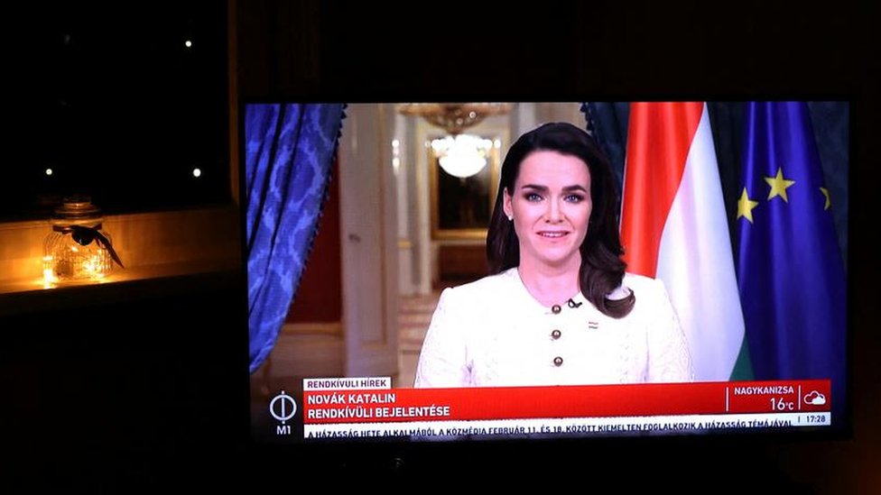 A screen shows the Hungarian President Katalin Novak as she announces her resignation