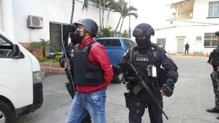 Norero marcha esposado custodiado por dos policías ecuatorianos.