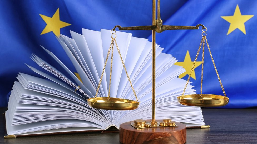 Весы и книги перед флагом ЕС