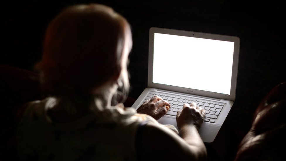   Silhouette of a person typing on a laptop 