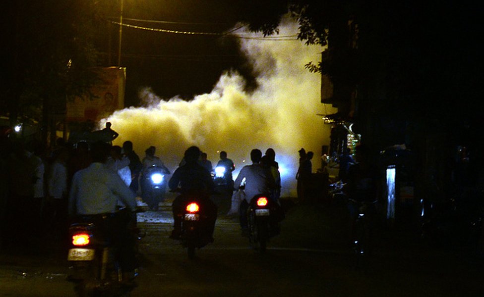 Pessoas passam pela fumaça da fumigação para afastar os mosquitos em Allahabad em 2016