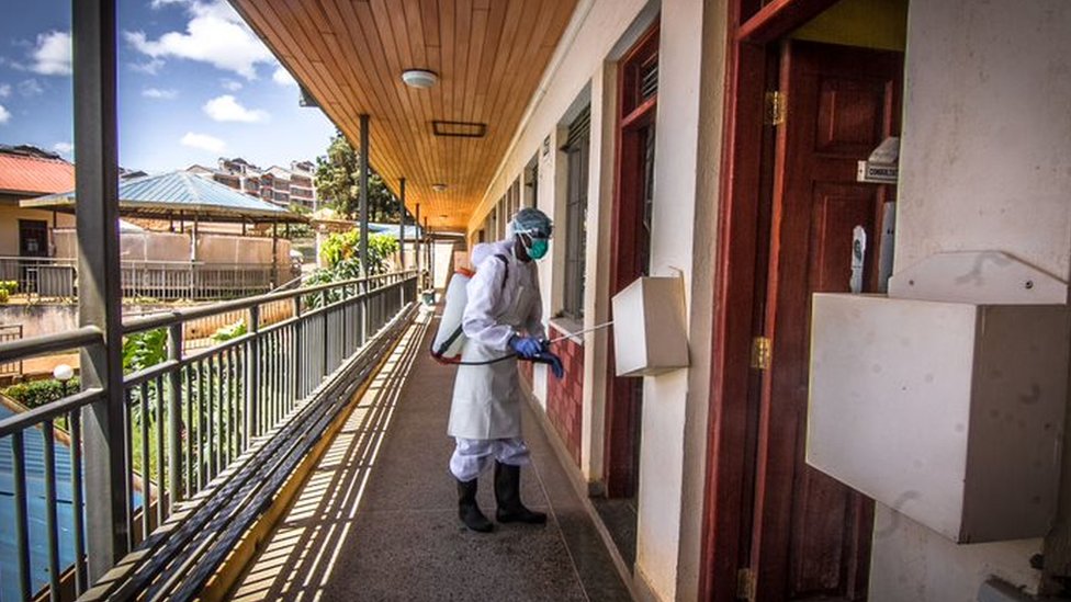A local health official wearing a protective suit disinfecting a health centre in Kibera Slums, in Nairobi