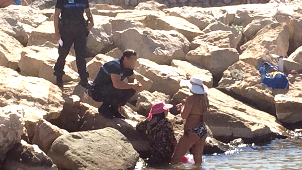 Женщина (в розовой шляпе) получает штраф на пляже в Каннах в понедельник