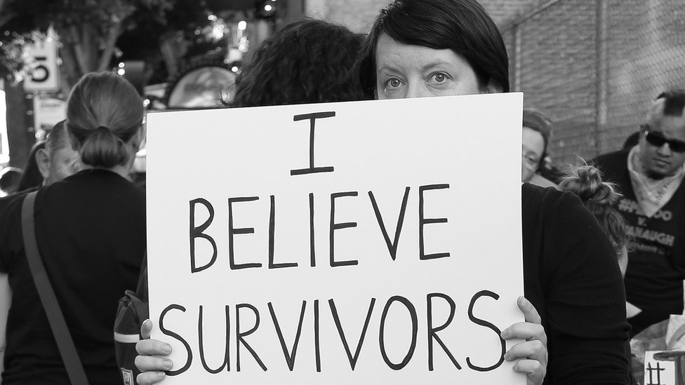 Mujer sosteniendo un cartel en defensa de las sobrevivientes de agresiones sexuales