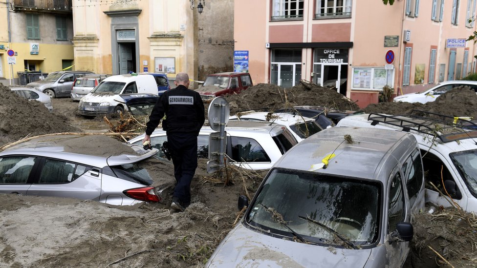 A police officer walks amongst vehicles submerged in mud in Breil-sur-Roya, south-eastern France