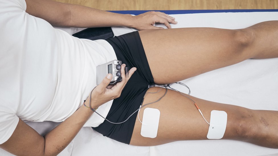 Una mujer usando un sistema de electroestimulación muscular.