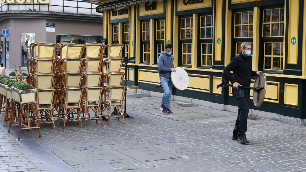 People carrying tables outside a closed restaurant in Brussels, Belgium