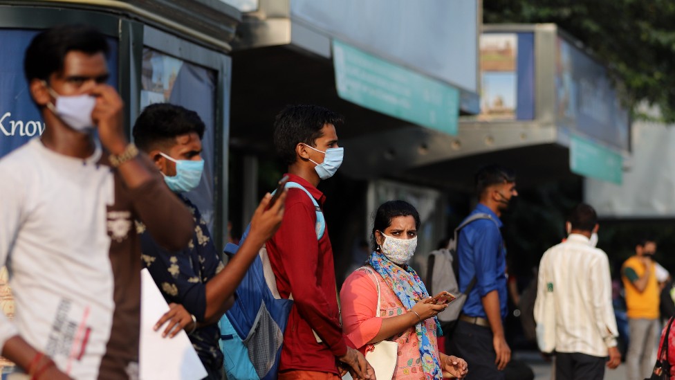 Gente en India con mascarilla esperando un autobús