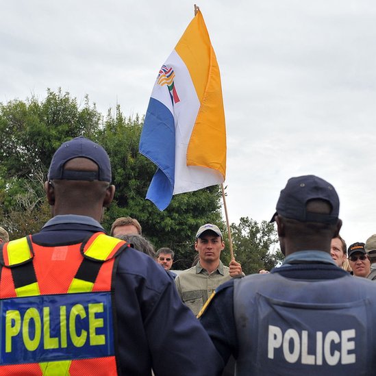 Sudafricanos que apoyan el movimiento de resistencia Afrikaner (AWB) de supremacistas blancos ondean la bandera que simboliza el apartheid frente a la policía en 2010.