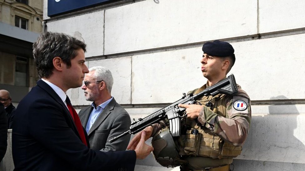 2024年3月25日，法國總理加布裏埃爾·阿塔爾（左）在訪問法國巴黎聖拉扎爾火車站時向一名執勤的法國士兵致意。
