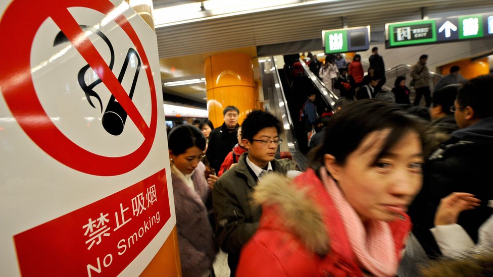 A woman in Japan passes by a "no smoking" sign