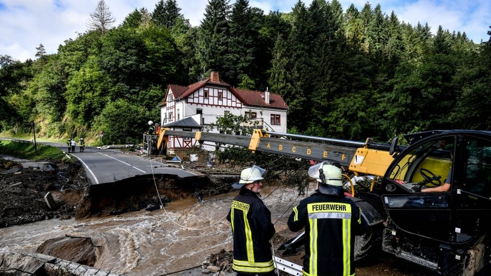 Firefighters next to a damaged road after flooding in Schuld, Germany