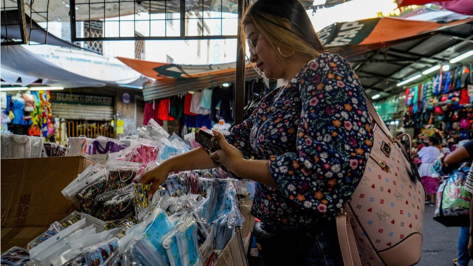 A woman buys masks at a market stall