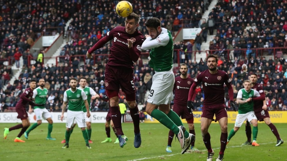 Игроки направляют мяч головой во время матча Hibs vs Hearts