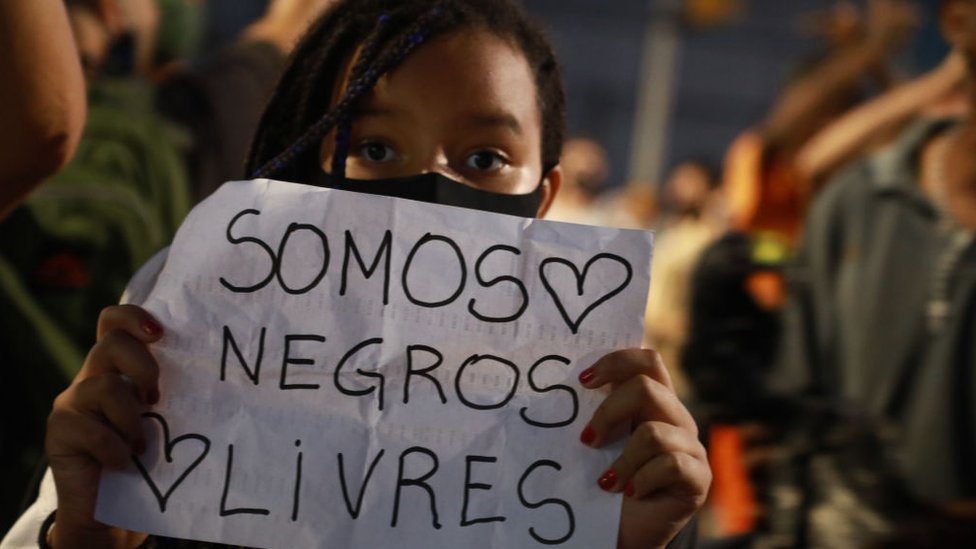Mulher segura carta escrito 'Somos negros livres' durante protesto