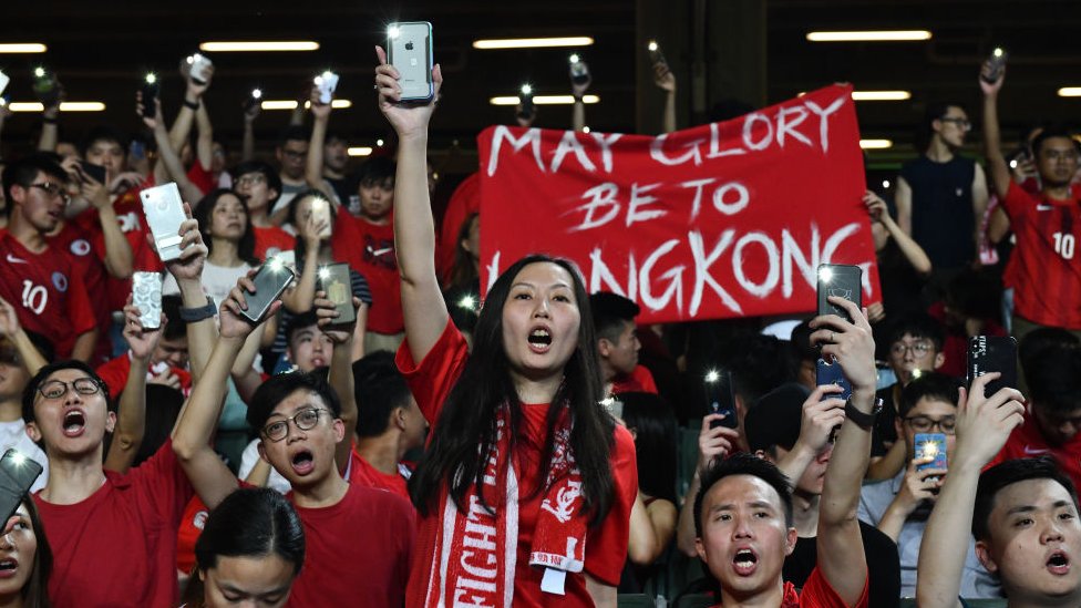 Футбольные фанаты держат свои телефоны и кричат ??во время акции протеста в конце отборочного матча чемпионата мира между Гонконгом и Ираном на стадионе Гонконга 10 сентября 2019 г.