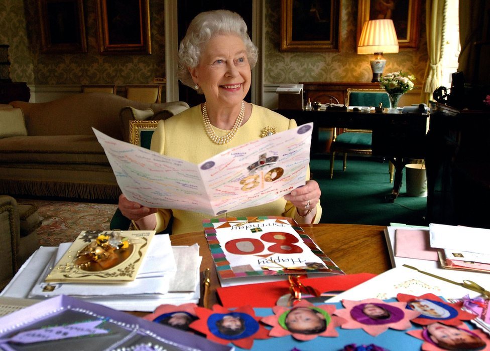 女王在倫敦白金漢宮的攝政室裏，看著她 80 歲生日時收到的一些賀卡