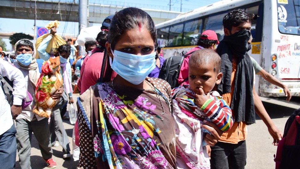 Женщина-мигрантка с ребенком в маске в качестве превентивной меры на автовокзале Ананд-Вихар во время общенациональной блокировки