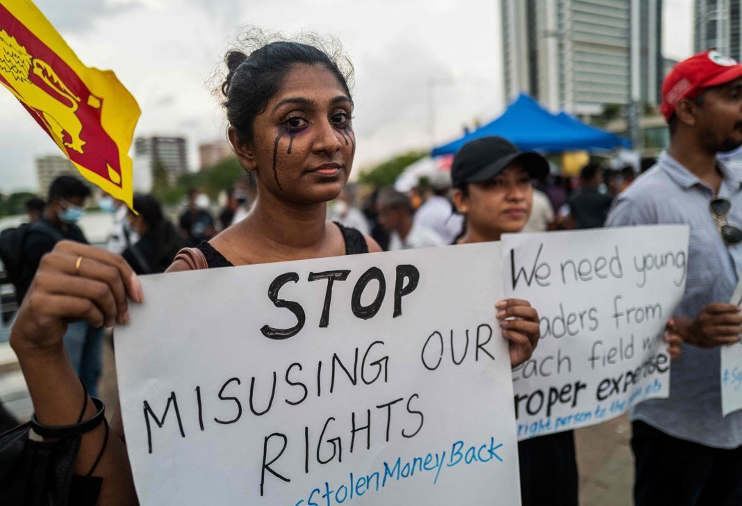 A woman holds a placard saying 'Stop misusing our rights', standing among protesters