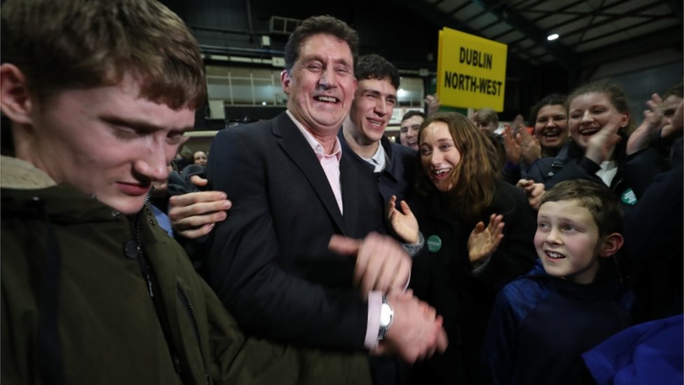 Лидер Партии зеленых Имон Райан окружен своей семьей, поскольку он избран в Южном округе Дублинского залива во время подсчета всеобщих выборов в Ирландии в RDS в Дублине.