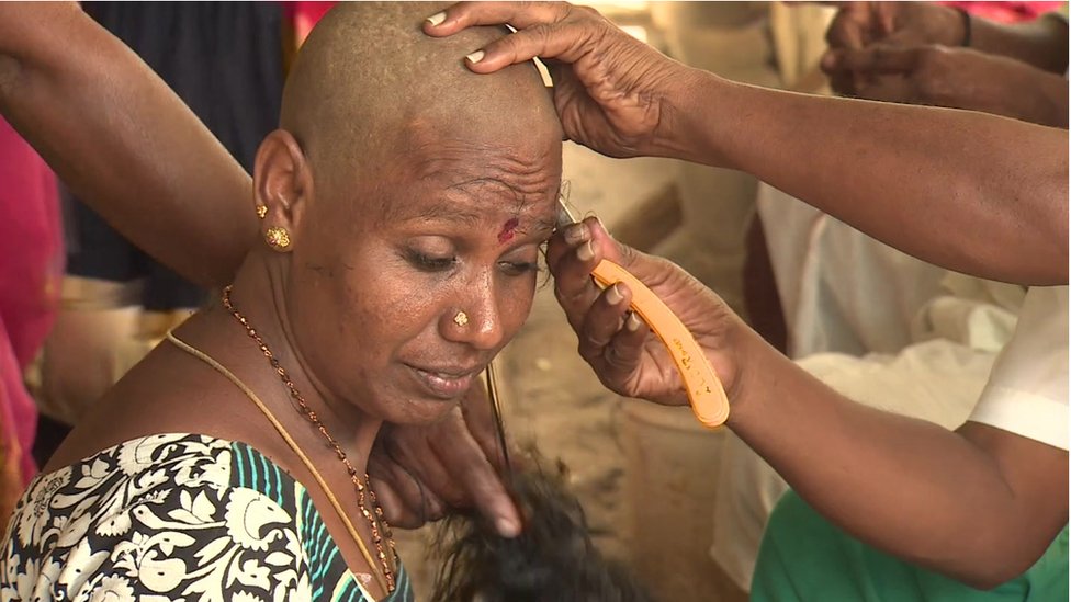 A woman in India having her head shaved