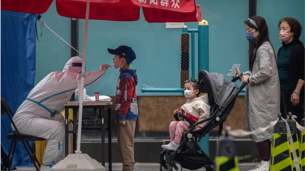 عامل صحي يأخذ مسحة من طفل صغير في بكين لإجراء فحص كوفيد.