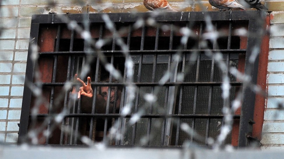 Un preso hace la señal de la victoria desde la ventana de una celda en Minsk, en 2011.