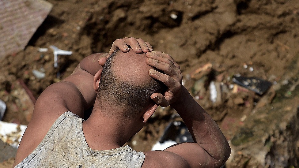 Hombre agarrándose la cabeza frente a su casa destruida por un deslave