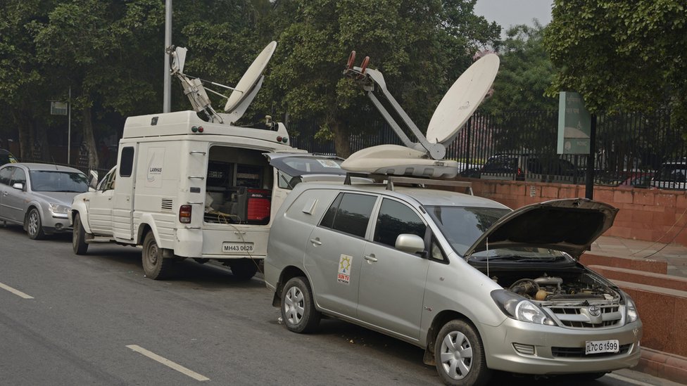 Фургоны со спутниковым телевидением припаркованы на улице в Дели