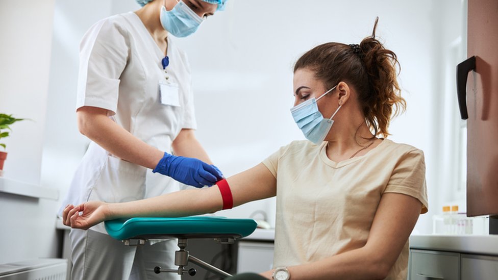 Una profesional de la salud prepara a una paciente para una toma de sangre