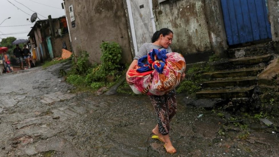 Женщина несет одежду, покидая место оползня в Гуаружа, штат Сан-Паулу, Бразилия. Фото: 3 марта 2020 г.