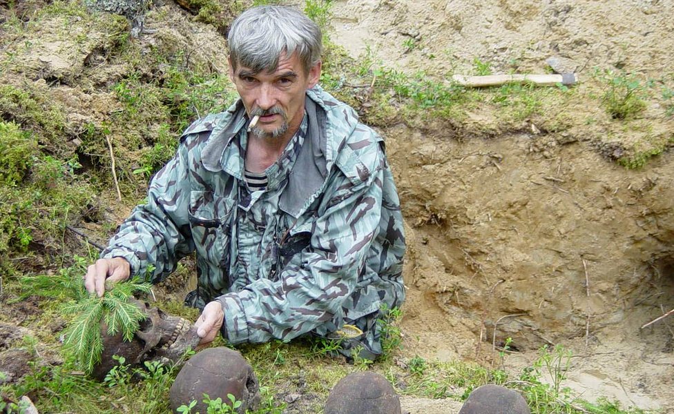 Юрий Дмитриев с черепами погибших на братской могиле