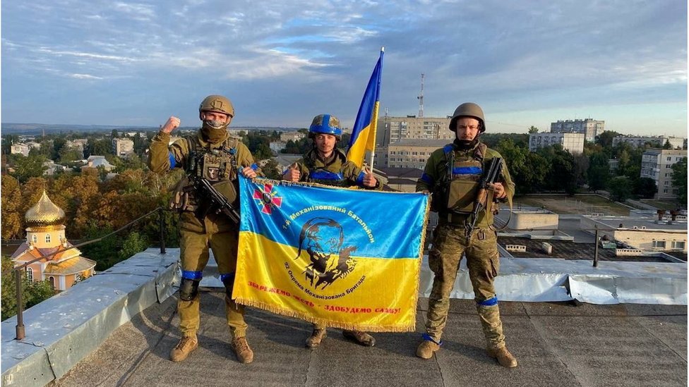 Ukrainian soldiers hold a flag at a rooftop in Kupiansk, Ukraine, Sept 10, 2022