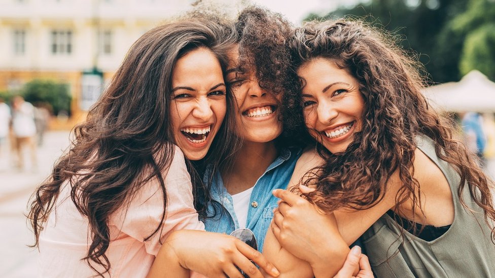 Three friends hugging and laughing