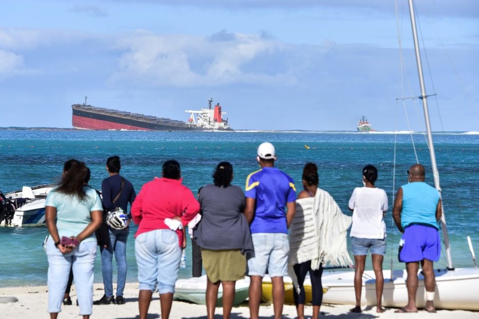 Люди на берегу смотрят на MV Wakashio 6 августа 2020 года.