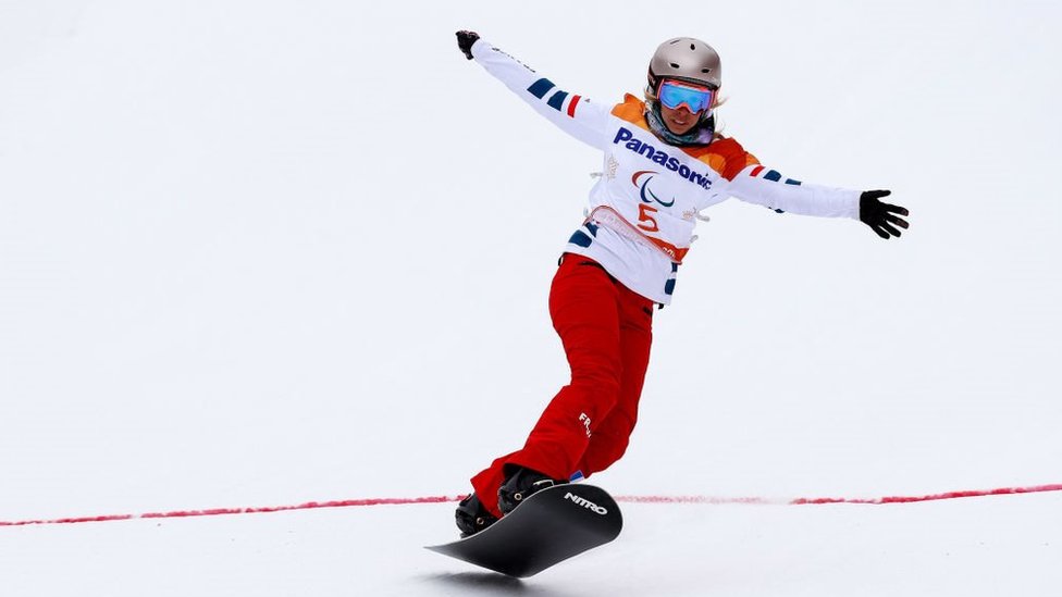 Cecile Hernandez snowboarding over the finish line at Pyeongchang in 2018