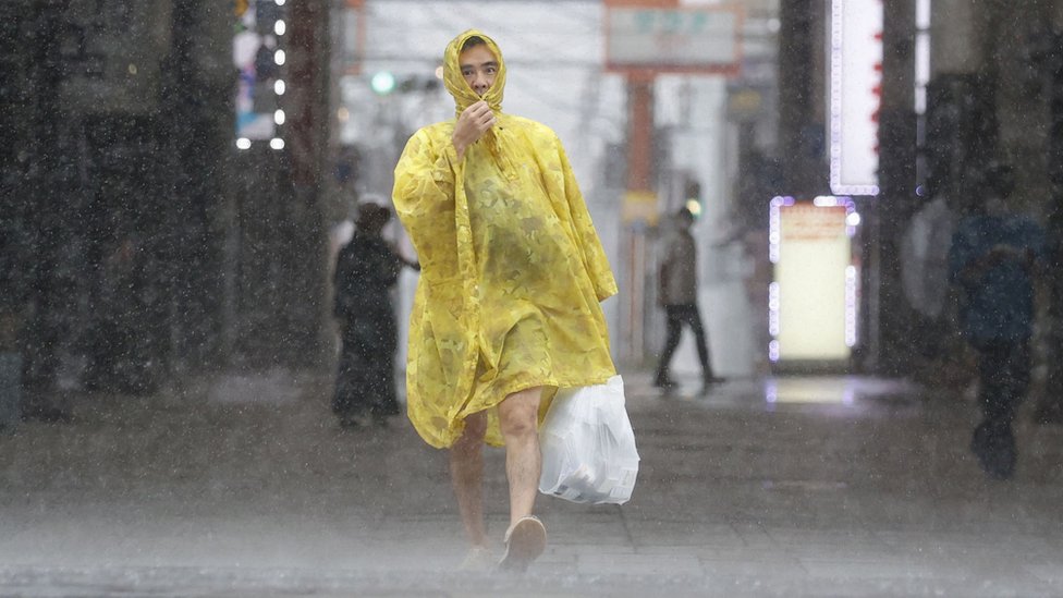 Un japonés con impermeable caminando bajo la lluvia