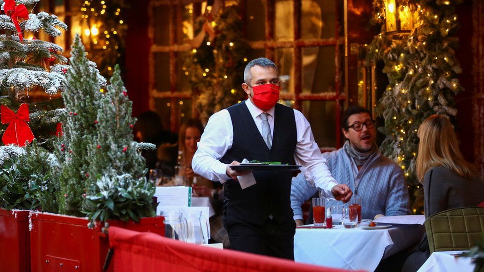 Официант в маске работает в ресторане в Лондоне