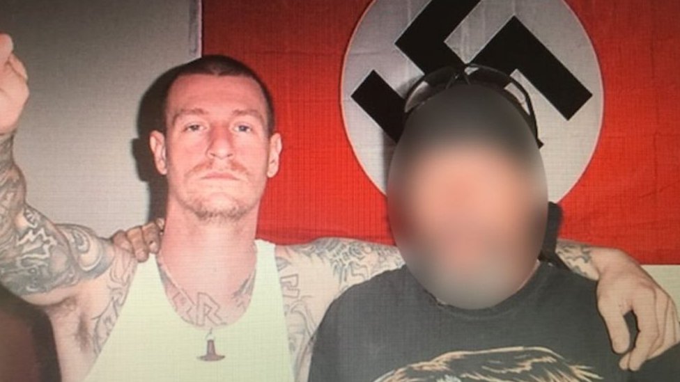 Kent fue neonazi durante 20 años Kent con una esvástica de fondo.
